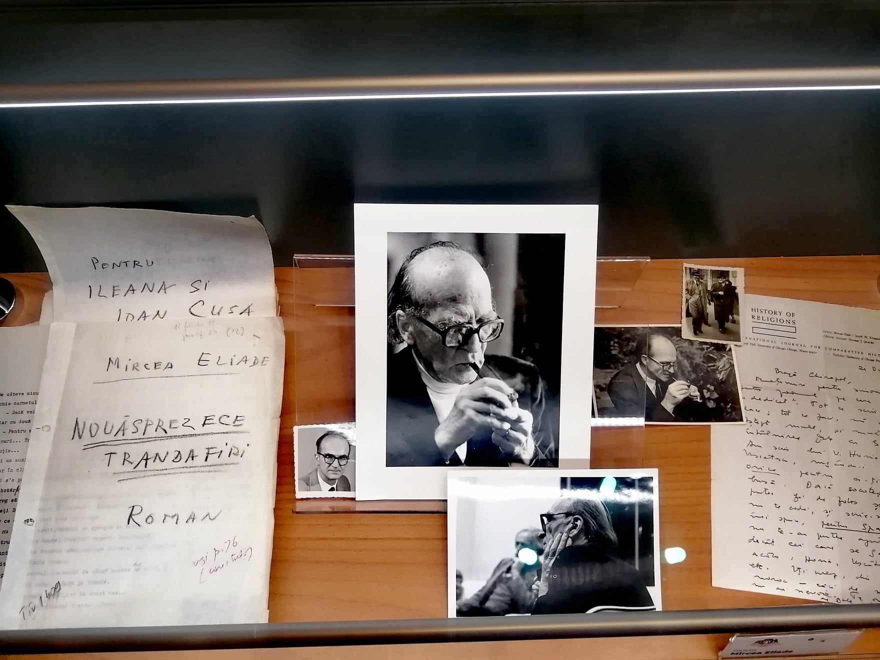 a glass museum case with photographs and hand-written notes