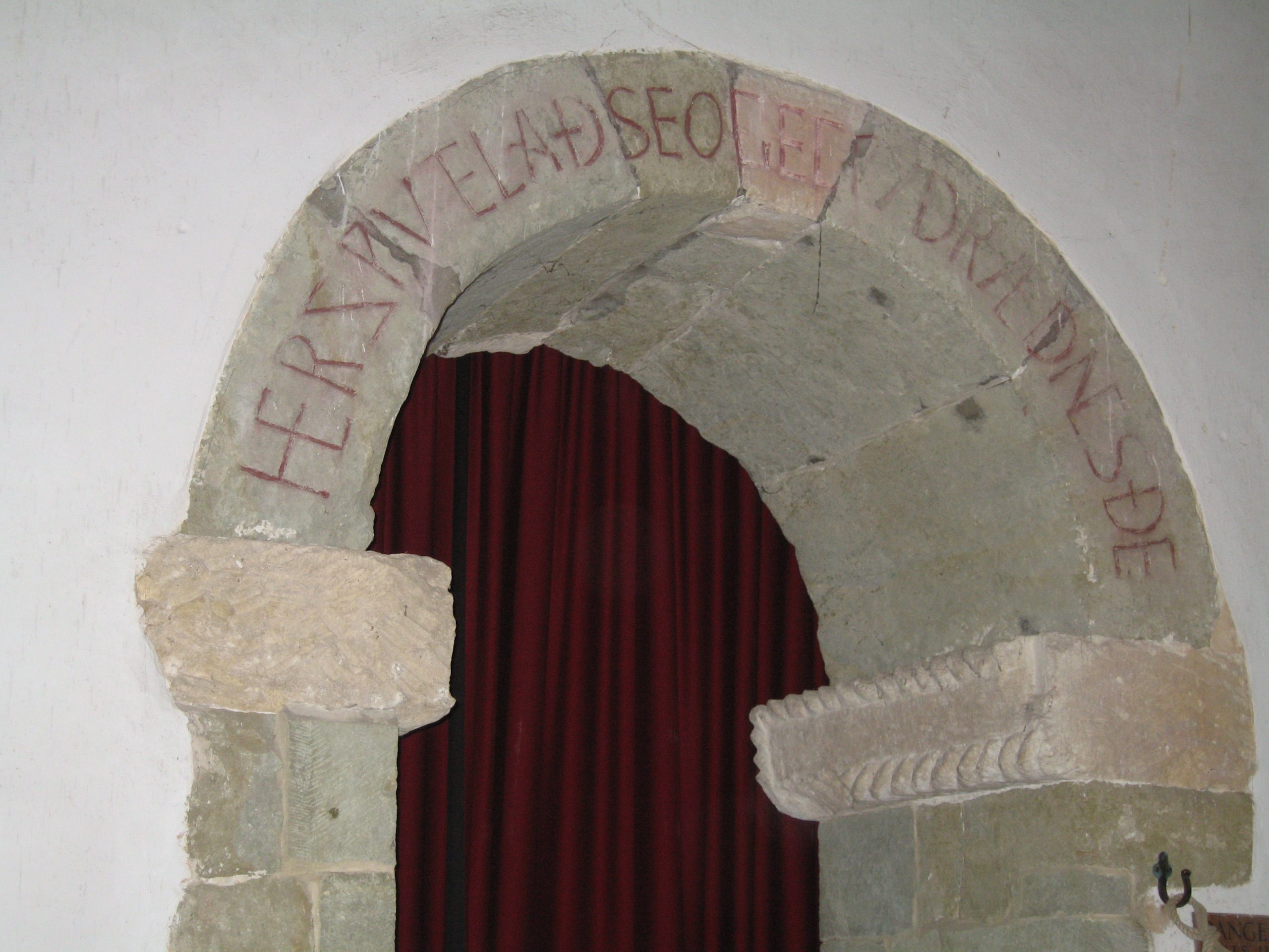 an arch in the doorway of a church with red lettering in old English