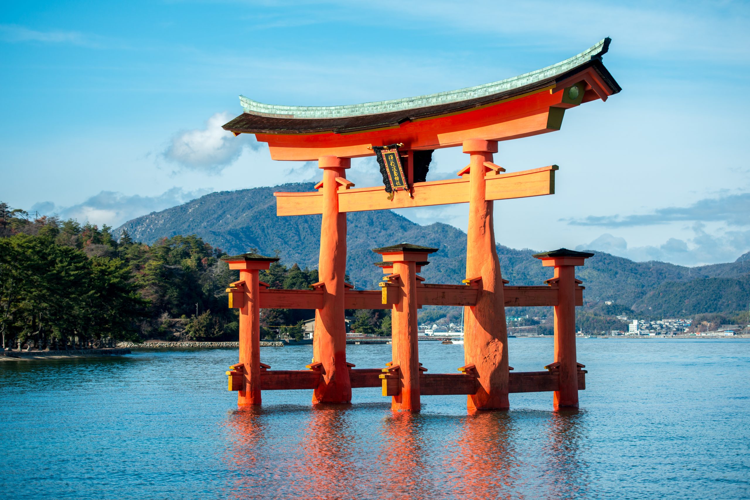 a red Shinto shrine in a pool of water with a mountain