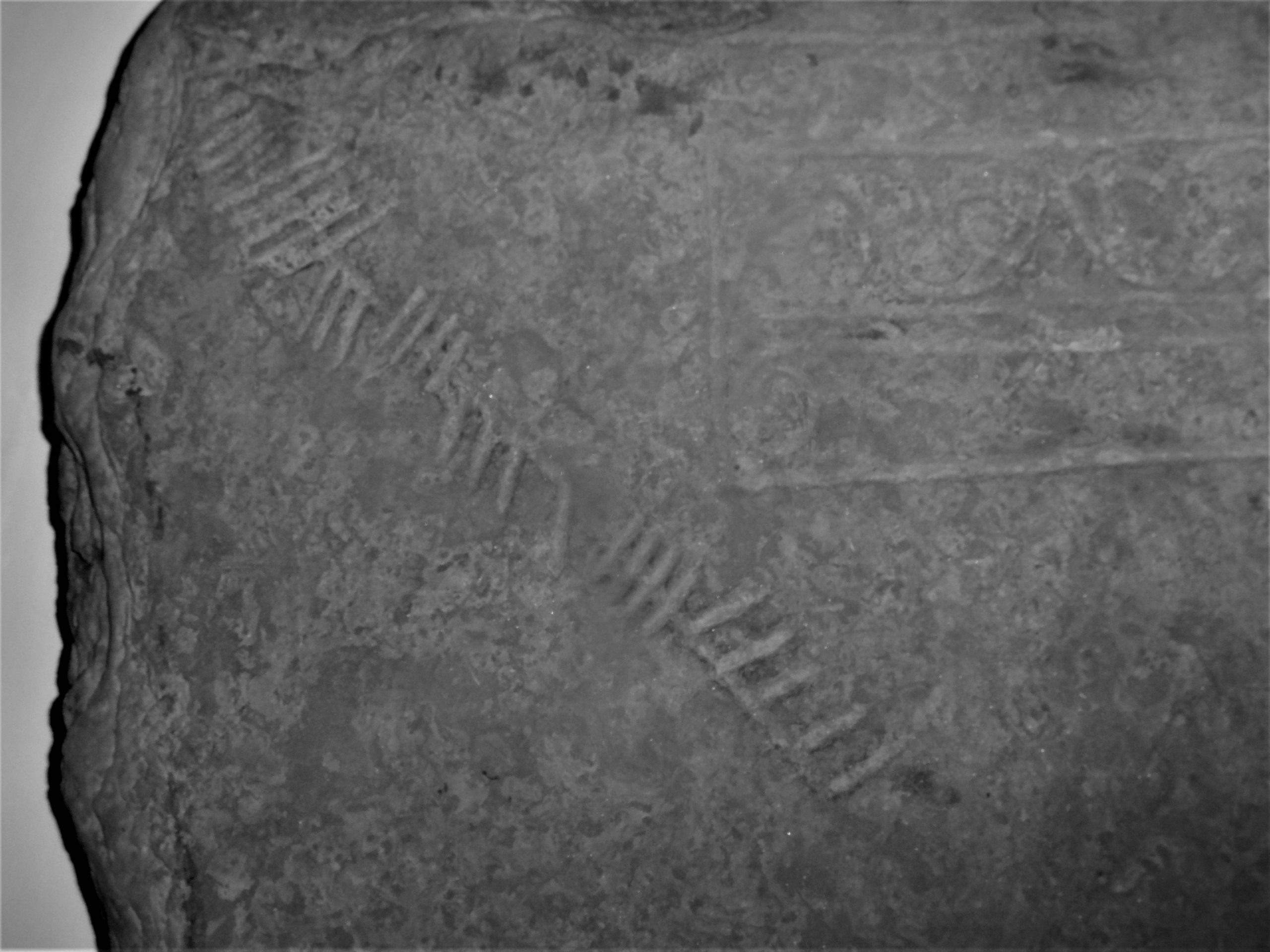 a grey stone marked with Ogham script of vertical lines.