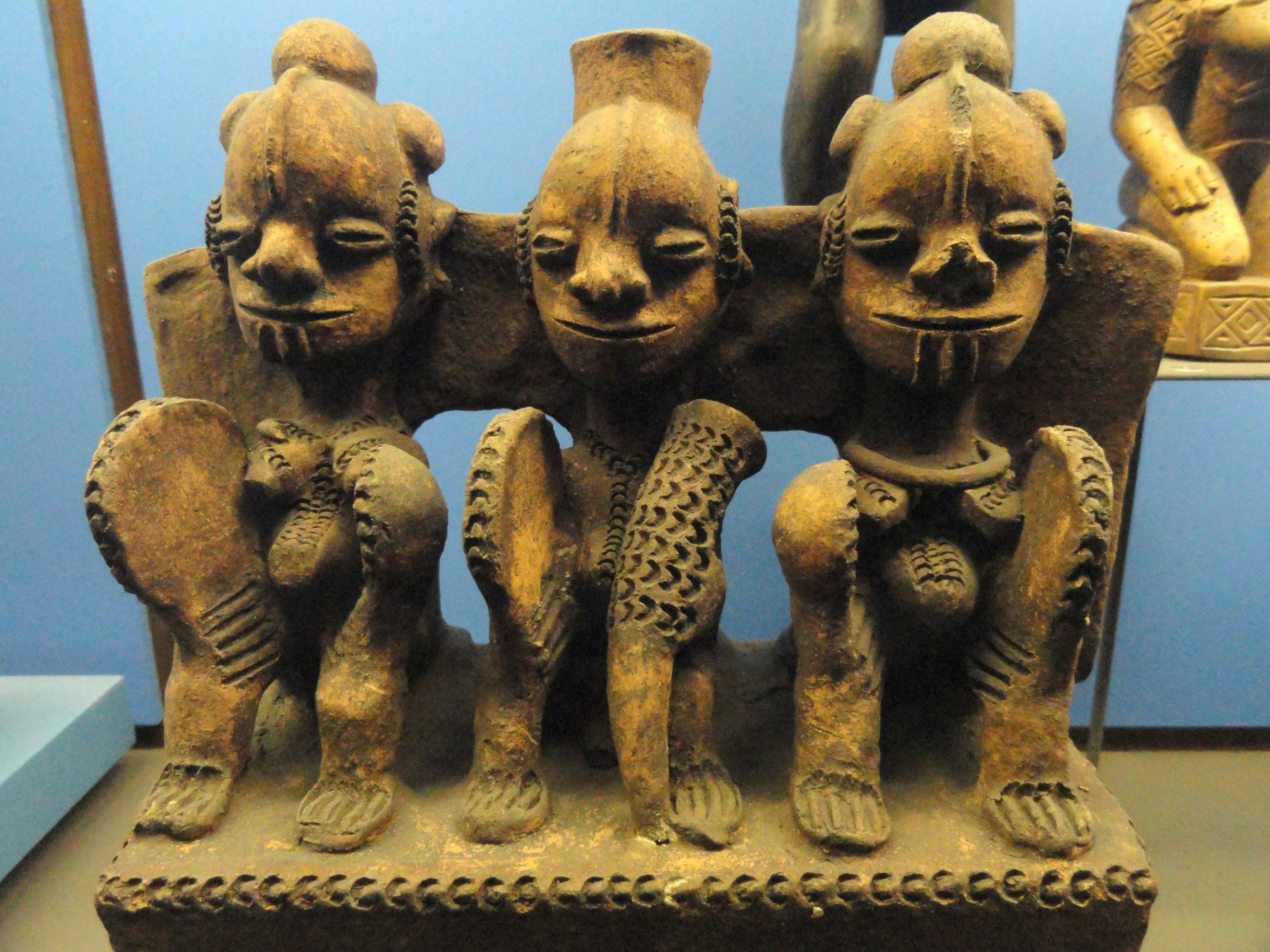 three African pottery figures crouch facing the viewer