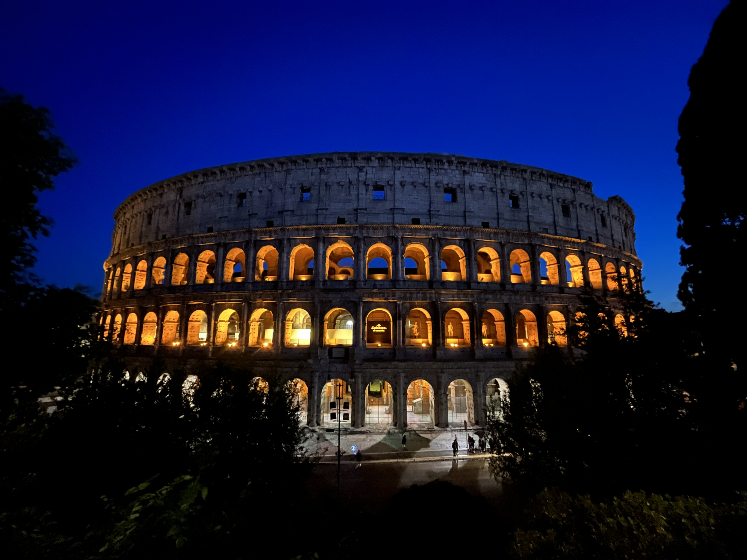 Roman Colosseum at night time, lit up against an evening sky