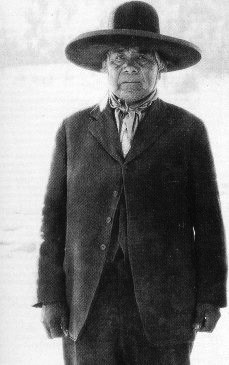 Historical portrait of an Indigenous man in suit and wide-brimmed hat.