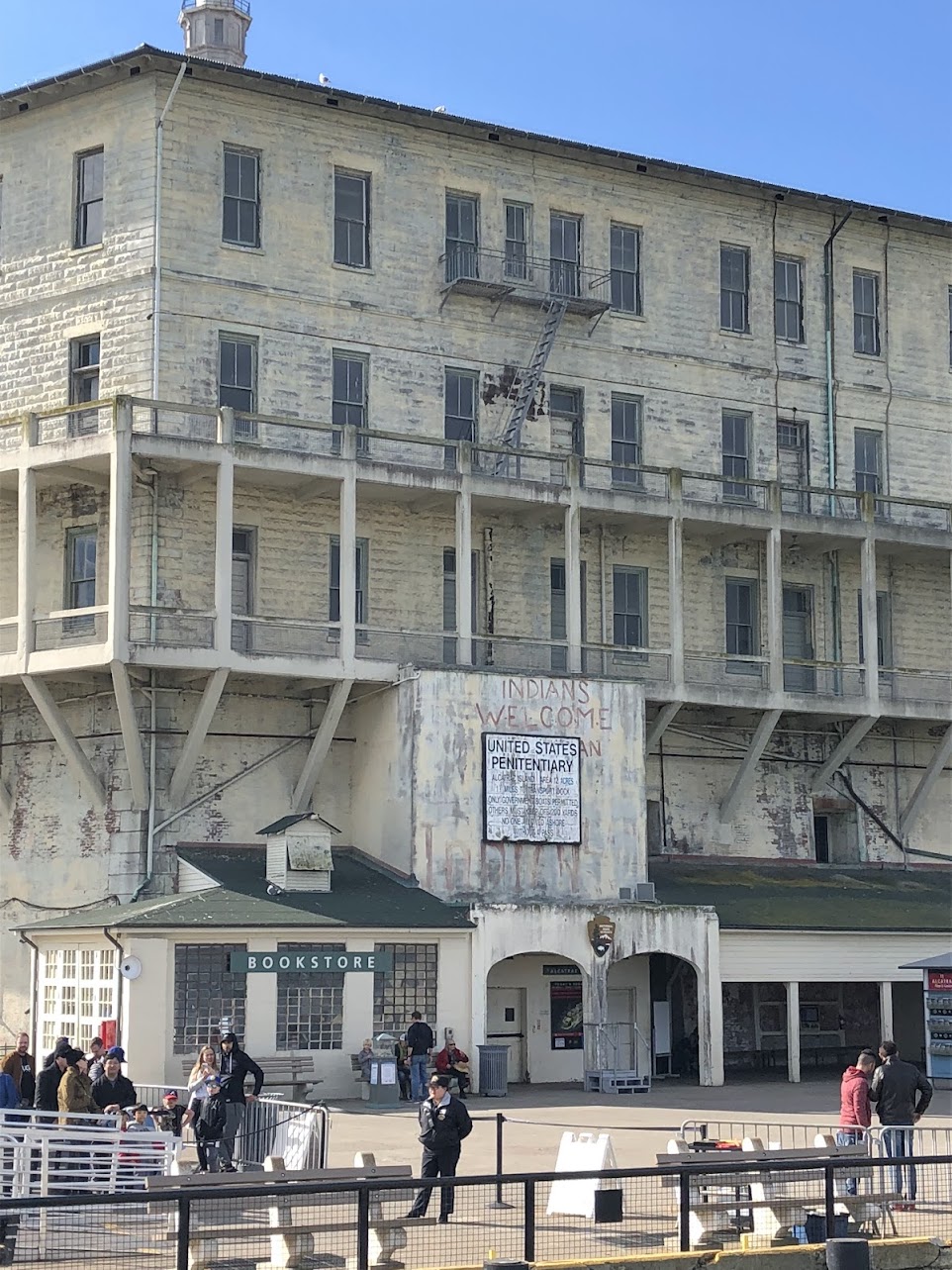 Alcatraz building facade with faded “Indians Welcome” graffiti above U.S. Penitentiary sign.