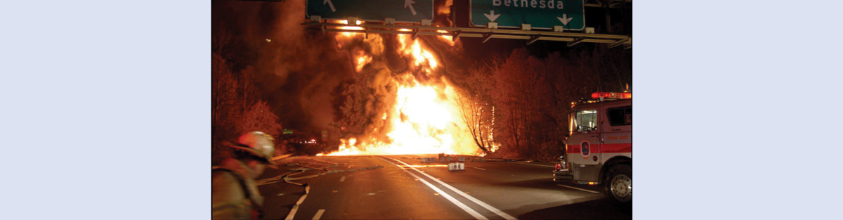 A picture shows a large ball of fire burning on a road. A fire truck and fireman are shown in the foreground.