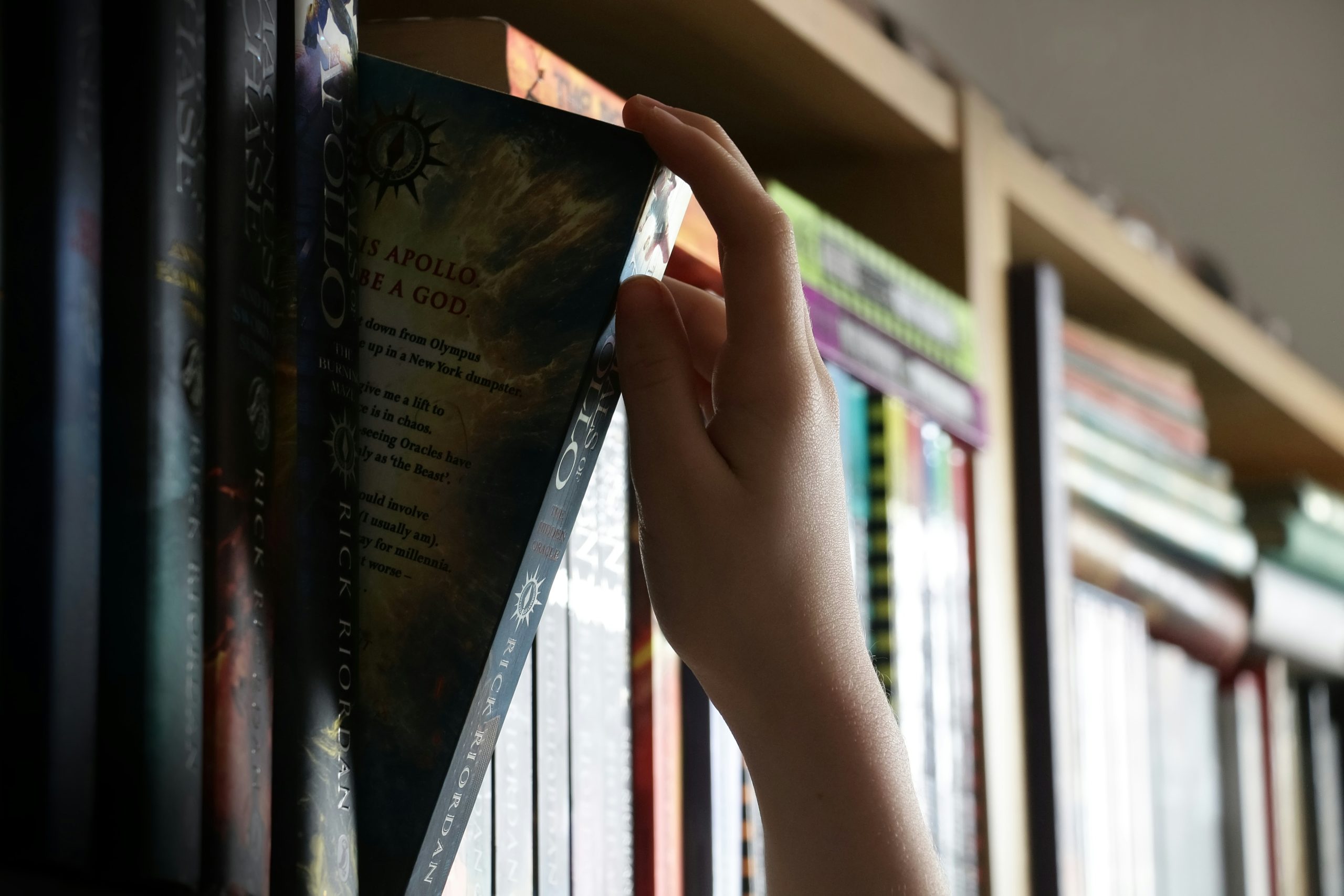 A hand pulls a book from a shelf